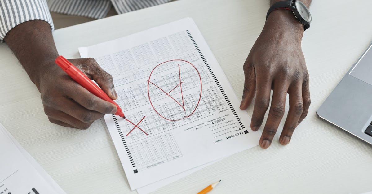 Close-up of a teacher marking a test paper with a red marker on a desk.